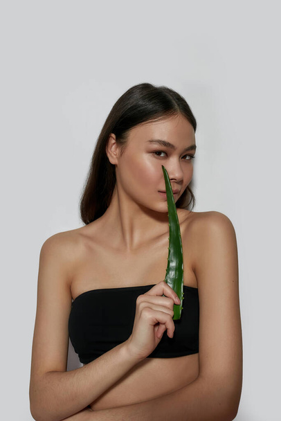 Sensual young asian woman holding green aloe leaf - Zdjęcie, obraz
