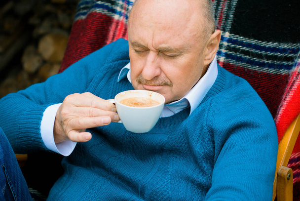 Felice uomo di età matura in maglione blu bere caffè a casa. Godetevi la vita Piacere Soddisfazione Felicità Concetto - Foto, immagini