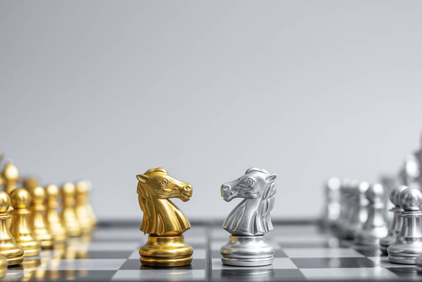 Satranç tahtasındaki altın ve gümüş satranç şövalyesi (at) rakip ya da düşmana karşı. Strateji, çatışma, yönetim, iş planlaması, taktik, siyaset, iletişim ve lider konsepti - Fotoğraf, Görsel