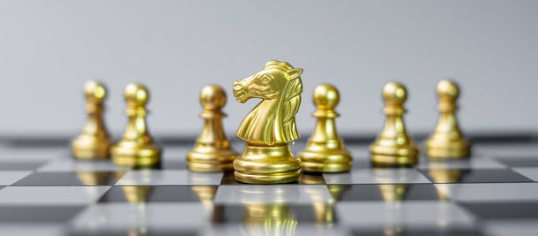 χρυσή φιγούρα ιππότης σκάκι Ξεχωρίστε από το πλήθος στο φόντο σκακιέρα. Στρατηγική, ηγεσία, επιχειρήσεις, ομαδική εργασία, διαφορετική, μοναδική και έννοια διαχείρισης ανθρώπινων πόρων - Φωτογραφία, εικόνα