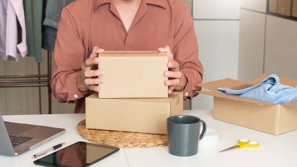Aziatisch ondernemer werken thuis met verpakking doos van zijn online winkel voor te bereiden om producten te leveren aan klanten, alfa generatie life style concept - Foto, afbeelding