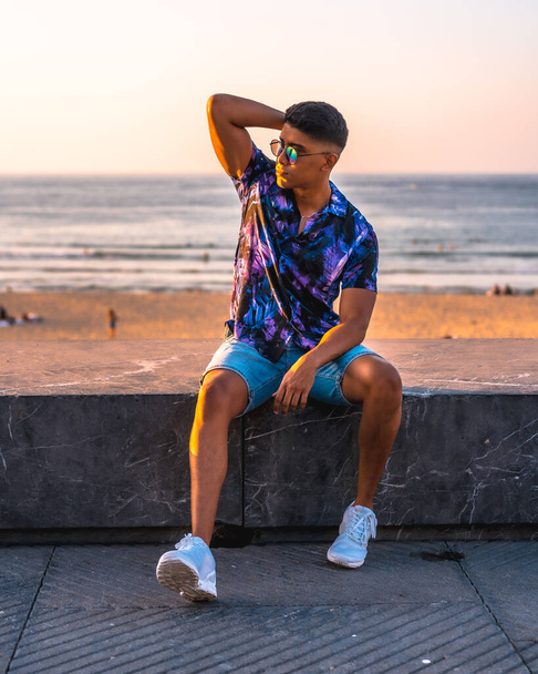 Summer lifestyle, portrait of a young Latino man enjoying summer vacation. with purple flower shirt and sunglasses - Фото, изображение