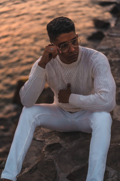 Summer lifestyle, a young Latino enjoying summer vacations. dressed in white with pants and sweater, enjoying the sunset, vertical photo - Fotografie, Obrázek