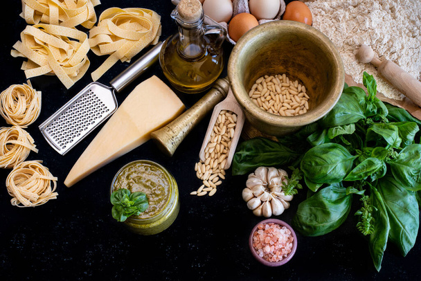 Preparing pesto sauce with parmesan cheese, basil, pine nuts and other ingredients. Meal preparation at the kitchen counter.  - Fotoğraf, Görsel