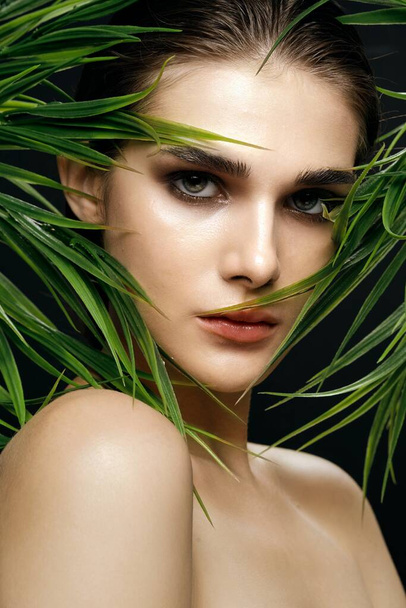 woman with bare shoulders green leaves cosmetology clean skin - Foto, Imagen