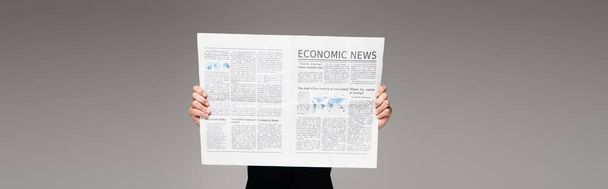 άνθρωπος καλύπτει το πρόσωπο, ενώ διαβάζετε οικονομικές ειδήσεις σε γκρι, πανό - Φωτογραφία, εικόνα