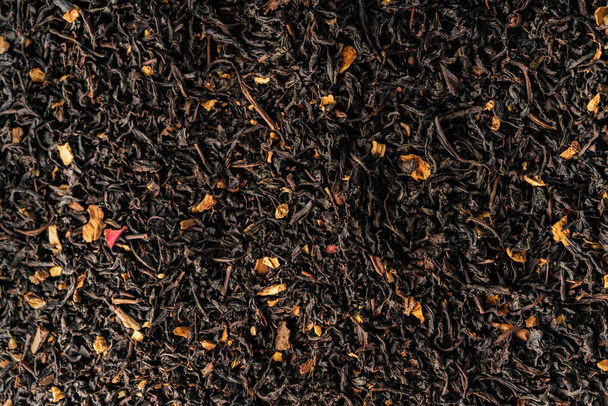 selektywne skupienie. tło żywności. naturalna czarna herbata do zaparzania liśćmi i kwiatami. widok z góry, z głębokimi cieniami. faktura. makro, przestrzeń kopiująca - Zdjęcie, obraz
