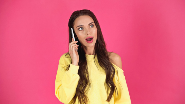 amazed young adult woman with open mouth speaking on cellphone isolated on pink - Fotoğraf, Görsel