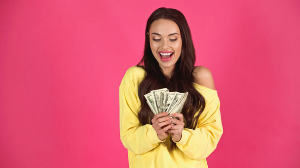 excited young adult woman holding dollar banknotes in hands isolated on pink - Foto, Imagen