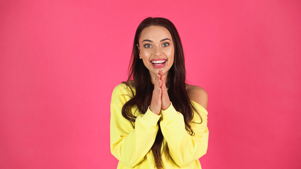 positive young adult woman in yellow blouse looking at camera with praying hands isolated on pink - Foto, Imagen