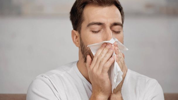 man with allergy sneezing in tissue at home - Fotografie, Obrázek