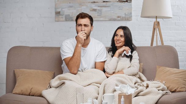 brunette woman holding tissue and smiling near sick boyfriend  - Photo, image