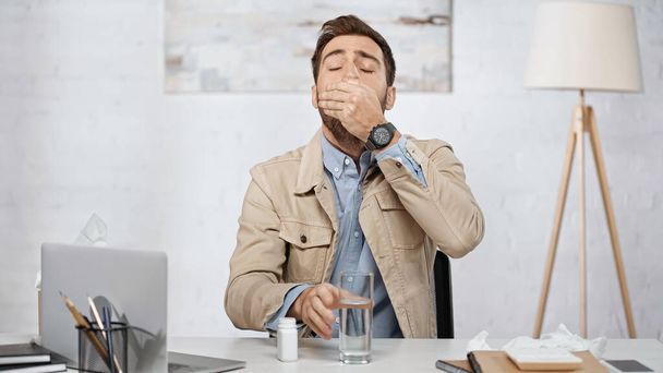 allergic businessman taking pill near laptop on desk  - Photo, image
