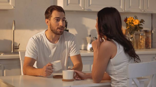 bearded man holding cup and talking with blurred girlfriend  - Foto, Imagem