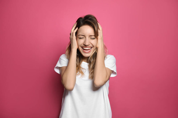 Cheerful young woman laughing on pink background - Photo, Image