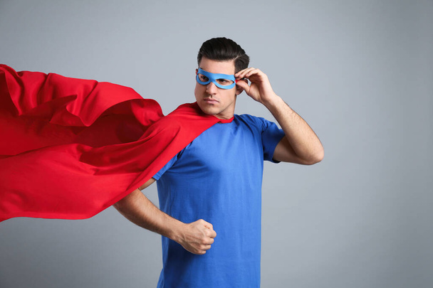 Man wearing superhero cape and mask on grey background - Φωτογραφία, εικόνα