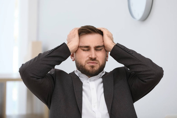 Young man suffering from migraine in office - Фото, изображение