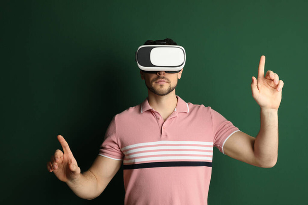 Man using virtual reality headset on green background - Foto, afbeelding