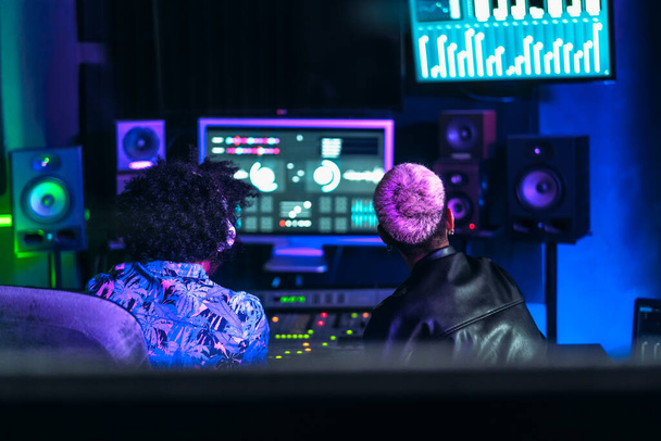 Giovani ingegneri audio che si divertono a lavorare con il controllo del pannello audio del mixer nello studio di registrazione musicale - Foto, immagini