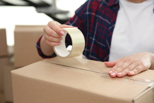 Woman taping cardboard box indoors, closeup. Moving day - Foto, immagini