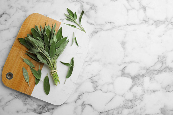 Board with fresh green sage on white marble table, flat lay. Space for text - Фото, изображение