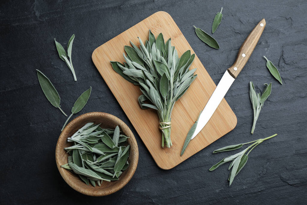 Fresh green sage with board, knife and bowl on black table, flat lay - Fotografie, Obrázek