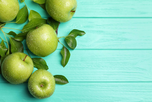 Fresh ripe green apples with water drops on turquoise wooden table, flat lay. Space for text - Fotoğraf, Görsel