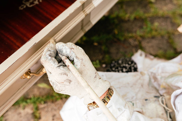 Detail der Hand mit schmutzigen Handschuhen malen mit dem Pinsel und Reparatur eines alten Holzmöbels. kleiner Handwerksbetrieb, handgemacht. Zimmerei. Restaurierung. - Foto, Bild