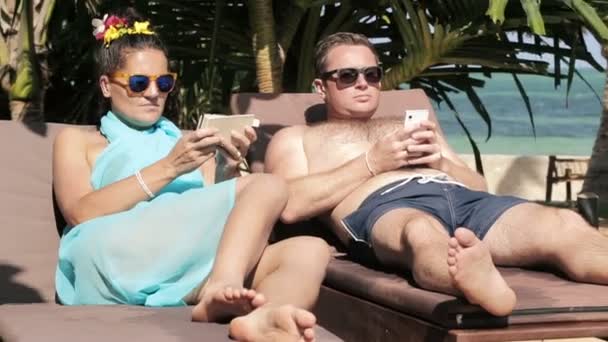 Couple with smartphones on sunbeds - Filmati, video