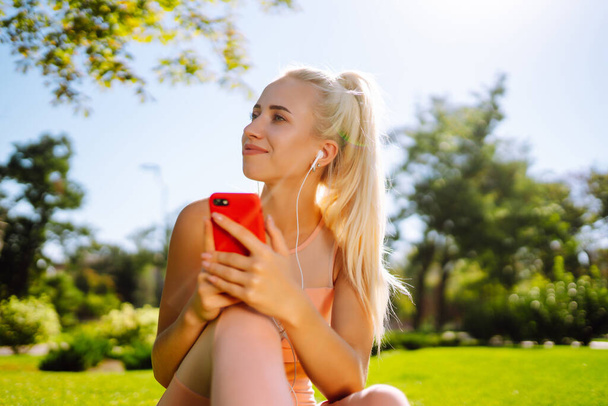 Young  yoga woman enjoy listening to music with headphone with feeling happy and relaxed in the park. Summer holidays, sport, vacation and lifestyle. - 写真・画像