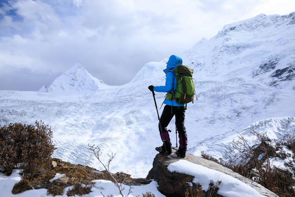 Successful woman backpacker hiking in winter mountains - Photo, Image