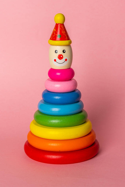 Kleurrijke kinderen stapelen speelgoed op gekleurde achtergrond. Houten ring stapelen clown voor peuters. De stapelaar staat op. - Foto, afbeelding