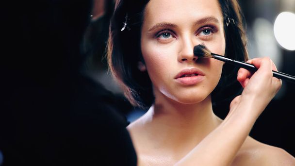 makeup artist εφαρμογή πούδρα προσώπου στο πρόσωπο του μοντέλου  - Φωτογραφία, εικόνα
