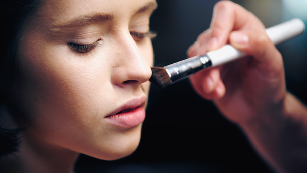 close up de maquiador aplicando base de maquiagem na pele do modelo com escova cosmética - Foto, Imagem
