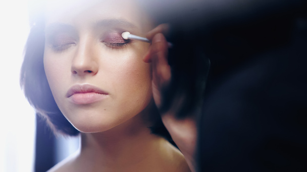 makeup artist applying eye shadow with cosmetic brush on woman with closed eyes - Fotografie, Obrázek