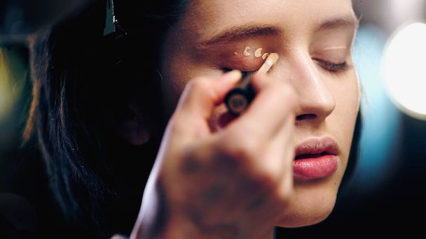 makeup artist εφαρμογή concealer στο βλέφαρο της γυναίκας - Φωτογραφία, εικόνα