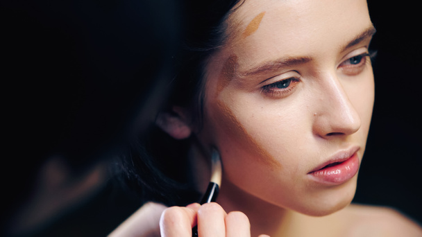 maquillador borroso haciendo rostro contorneante de modelo con cepillo cosmético - Foto, Imagen