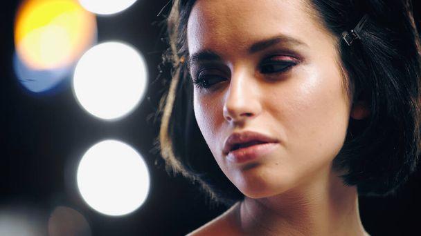 woman with makeup looking away with back light on blurred background - Photo, Image