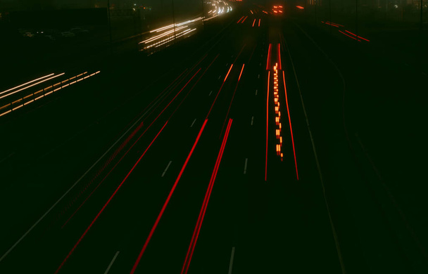 Blurred traffic lights on the highway at night. Fog rising in the background. Bokeh, background, moody and vintage filter - Photo, Image