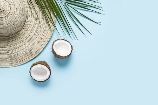 Women's hat with wide brim, sunglasses, coconut and a branch of a palm tree on a blue background. Summer concept, vacation at sea. Banner. Flat lay, top view. - Photo, Image