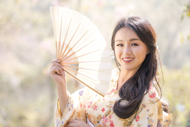 Ανθισμένες κερασιές και Ασιάτισσα που φοράει κιμονό. Όμορφη Γυναίκα φοράει παραδοσιακό ιαπωνικό κιμονό με άνθη κερασιάς την άνοιξη, Ιαπωνία. - Φωτογραφία, εικόνα