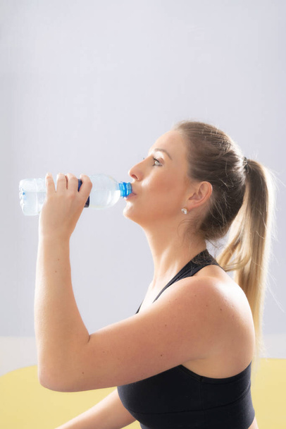 Fitness woman drinking water, white  backgound, high key. - Photo, Image
