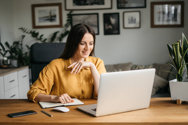 Κεφάλι πυροβόλησε ευχάριστη ευτυχισμένη νεαρή γυναίκα ελεύθερος επαγγελματίας που εργάζονται στον υπολογιστή στο σπίτι. Ελκυστική επιχειρηματίας που σπουδάζει online, χρησιμοποιώντας λογισμικό laptop, web surfing πληροφορίες ή ψώνια στο internet store. - Φωτογραφία, εικόνα