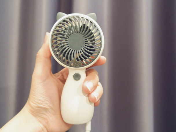 Photo d'une main humaine tenant un ventilateur portable blanc - Photo, image