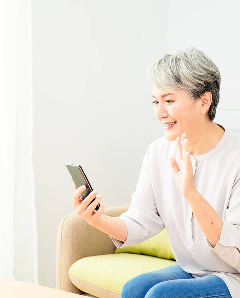 Happy mature senior asian woman holding smartphone using mobile online apps. - Valokuva, kuva