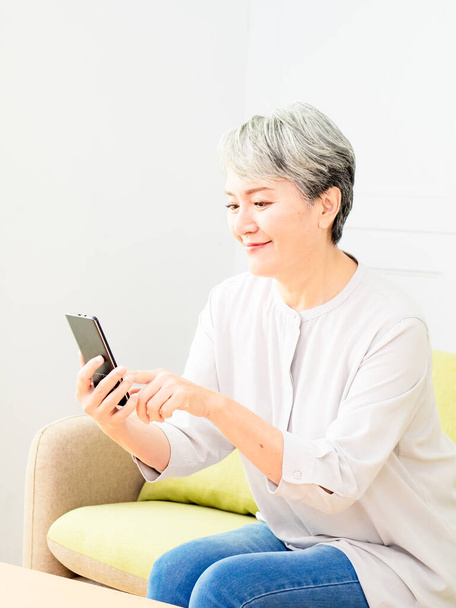 Happy mature senior asian woman holding smartphone using mobile online apps. - Photo, image