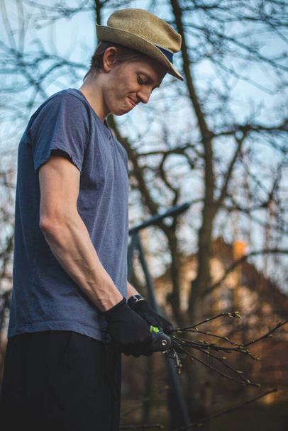 A keményen dolgozó férfi munkaruhában aprítókat használ, hogy kisebb botokra hasítsa a fát, hogy beférjen a kemencébe elégetni. Dolgozz a kertben. Szépítem a terepet. A gyümölcsösök szépítése. - Fotó, kép