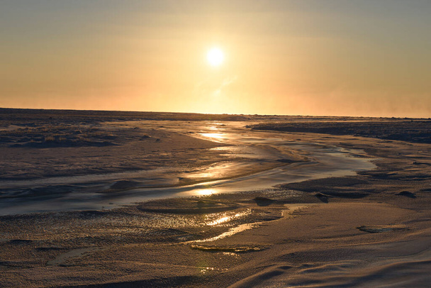 Sarkvidéki táj télen. Kis folyó jéggel Tundrában. Naplemente. - Fotó, kép