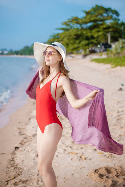 Portrait of beautiful woman in red swimsuit relaxing on the beach  - Fotó, kép