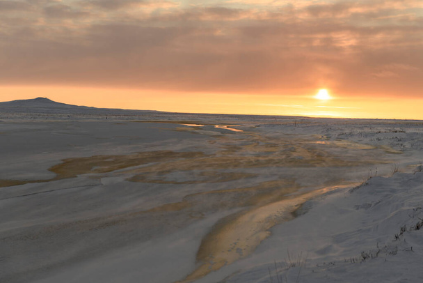 Арктический ландшафт зимой. Маленькая река со льдом в тундре. Закат. - Фото, изображение